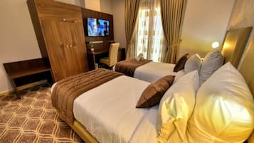 Habitación de hotel con dos camas, televisor, escritorio y armario.