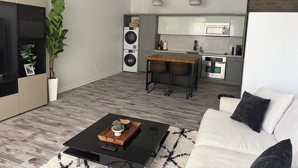 Uma sala moderna com uma mesa de centro preta, um sofá e uma área de cozinha com uma mesa de jantar.