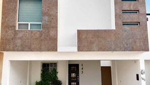 A modern two-story building with a flat roof, a central entrance, and a tiled driveway. - Entire House | Escobedo | North Monterrey (Ciudad General Escobedo)