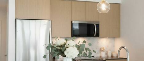 Una cocina moderna con electrodomésticos de acero inoxidable, una isla blanca y un jarrón con flores.