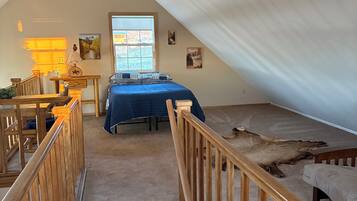 Une chambre à coucher avec un lit, un bureau, une chaise, une fenêtre et un escalier.