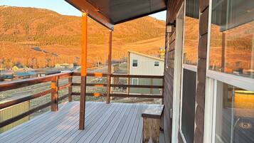 Une terrasse en bois avec un banc, un espace abrité et une vue sur un paysage vallonné.