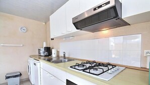 Cocina compacta con estufa a gas, microondas y cafetera.