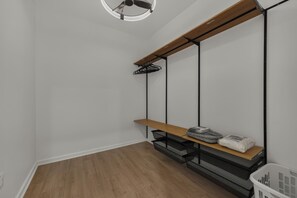 Ein Zimmer mit einer hölzernen Bank, schwarzem Metallregal und einer weißen Wand.