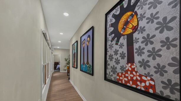 A hallway with framed artwork on the walls, a wooden floor, and a door at the end. - Design Lover’s 1br Suite (Atlanta)