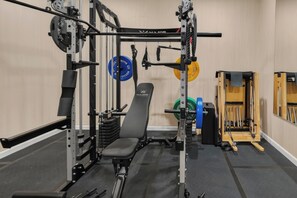Ein Fitnessraum mit Gewichteinrichtung, einer Bank und einem Squat-Gestell.