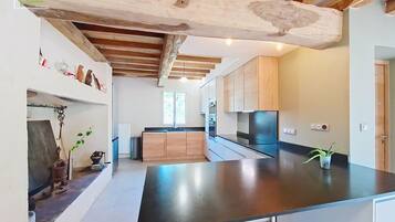 Une cuisine moderne avec des poutres en bois, un plan de travail noir et des armoires en bois.