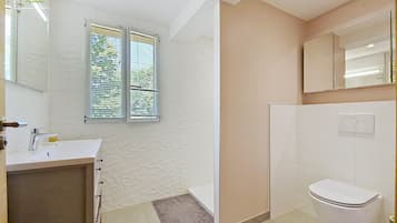 Une salle de bain avec un lavabo, des toilettes et une fenêtre équipée de stores.