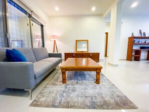 A living room with a sofa, a wooden coffee table, a lamp, a mirror, and a cabinet. - Sueños del Mar 2 (Playa del Carmen)