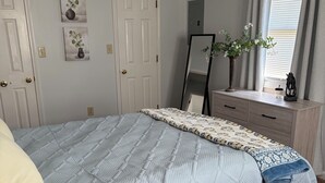 Un dormitorio con cama, cómoda, espejo y puerta.