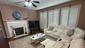Ein Wohnzimmer mit Kamin, Fernseher, Sofa und Deckenventilator.