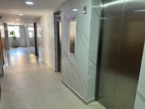 A hallway with marble walls, a reception desk, and an elevator. - Edificio Sagitario - Calidad & Precio (Cartagena de Indias)