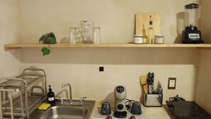 Uma cozinha com pia, escorredor de louça, cafeteira, liquidificador e diversos utensílios de cozinha.