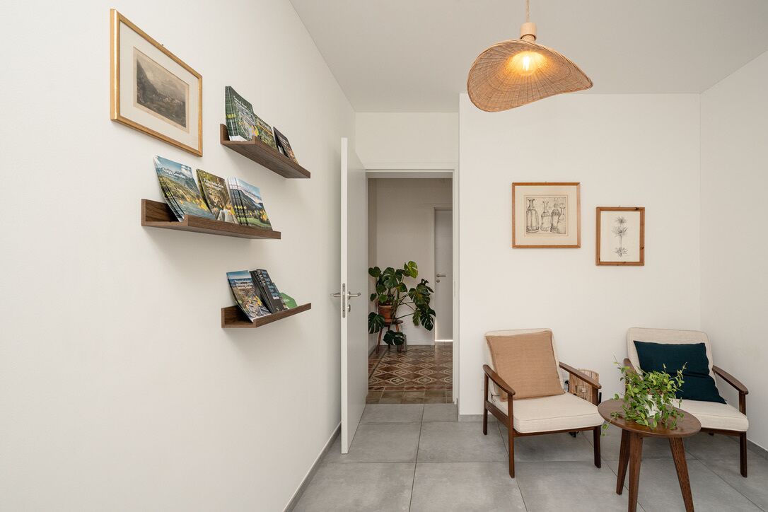 A hallway with a door leading to a room, a hanging light fixture, and two chairs with a small table.