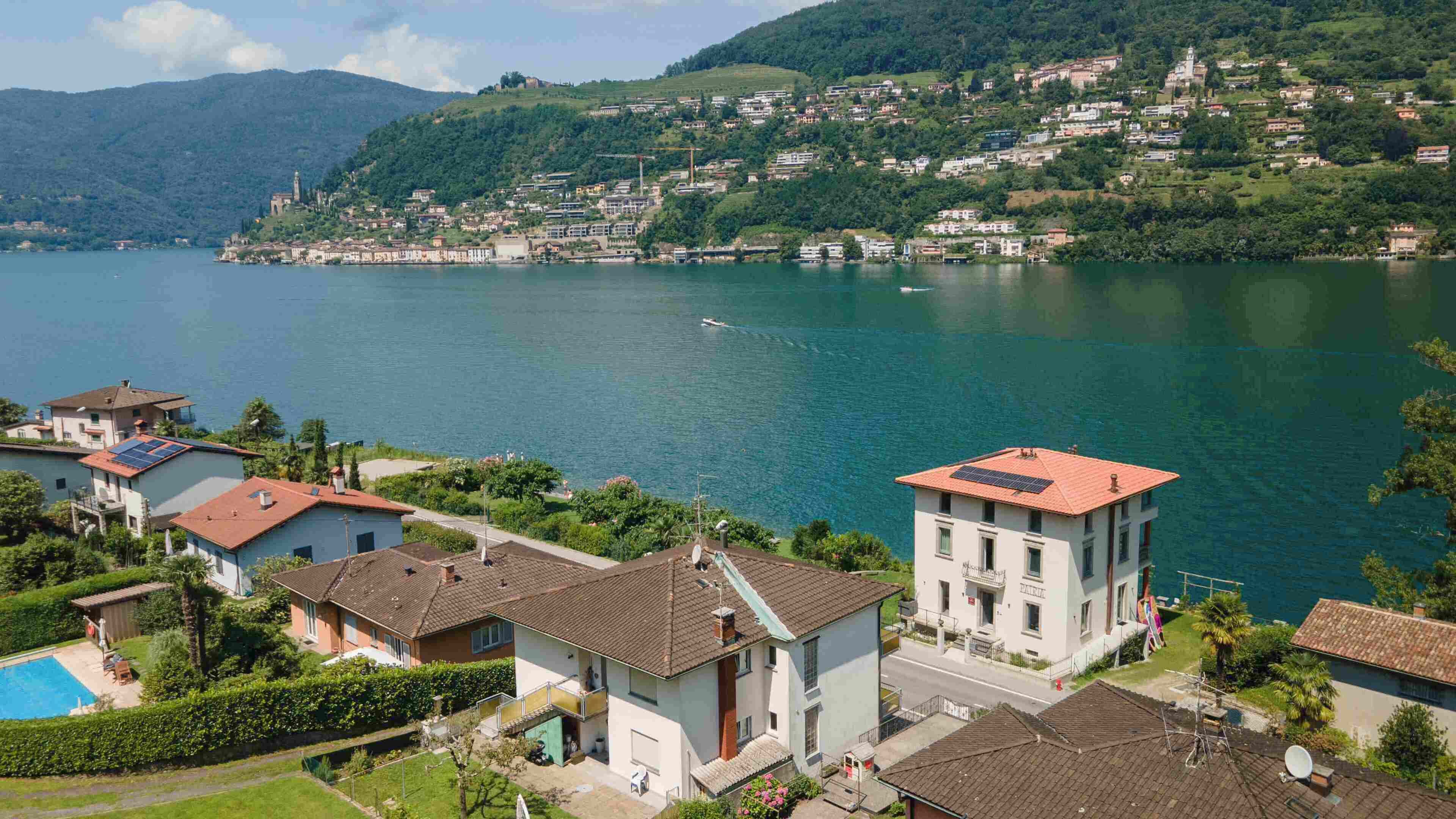Un barrio residencial con casas, piscina y vistas a un lago y colinas.