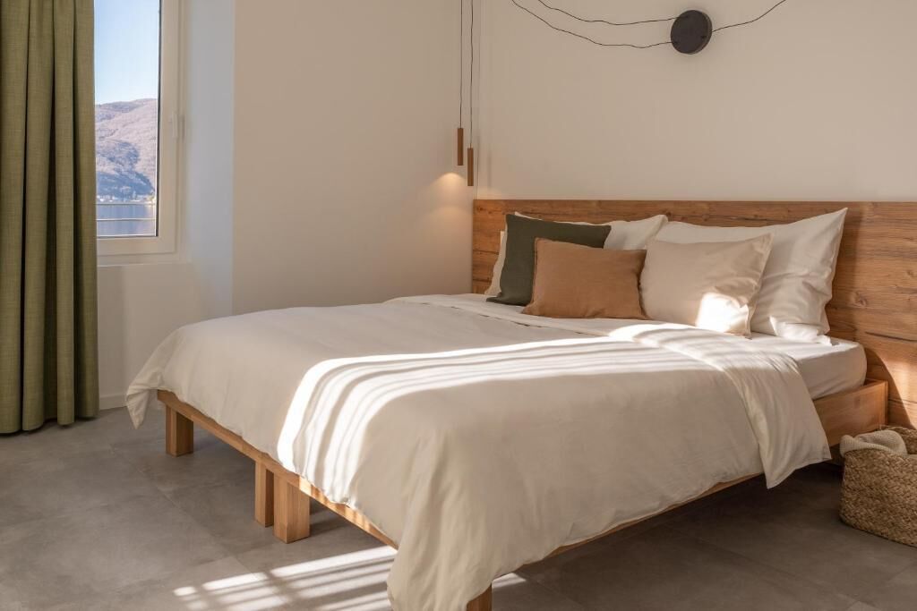 A bedroom with a wooden bed, a view of the outdoors, and a simple wall decoration.