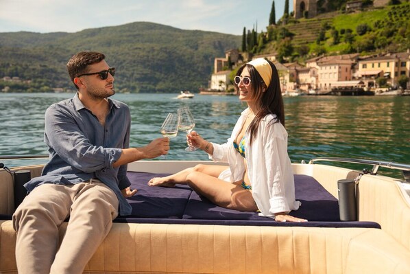 A couple on a boat with a view of a lake and buildings in the background.