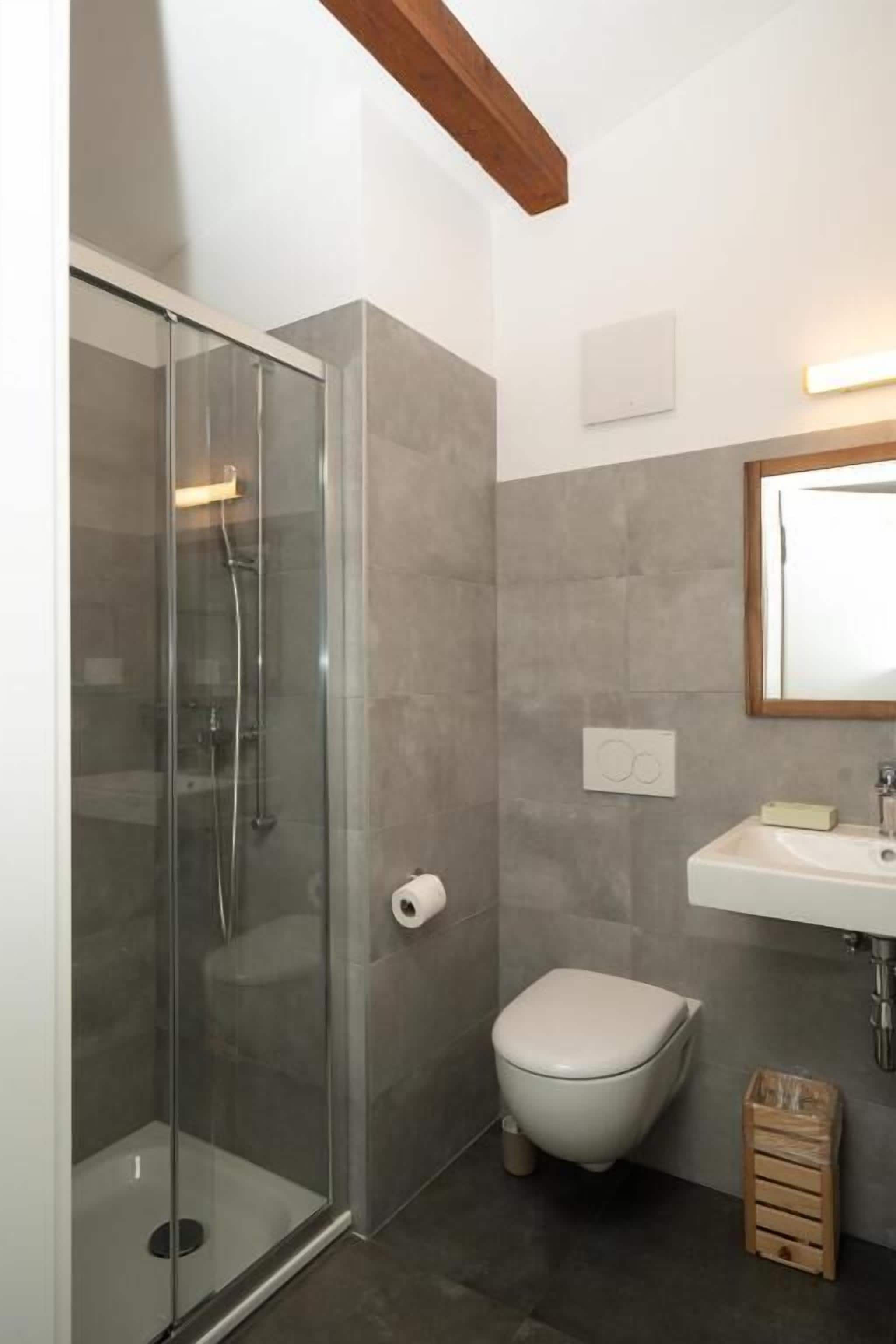 A bathroom with a glass-enclosed shower, a toilet, and a sink.