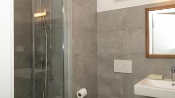 A bathroom with a glass-enclosed shower, a toilet, and a sink.