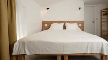 A single-bed room with a wooden headboard, white bedding, and a small bedside table.