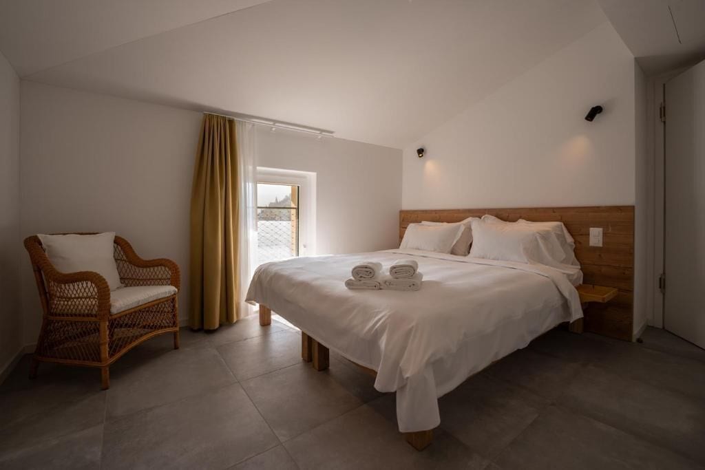 Un dormitorio con cama, una silla y una ventana.