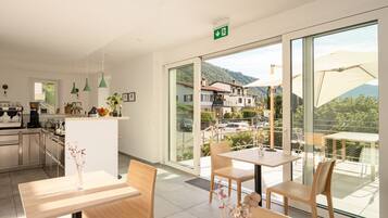 Ein modernes Hotelzimmer mit Küche, Essbereich und einem Balkon mit Bergblick.