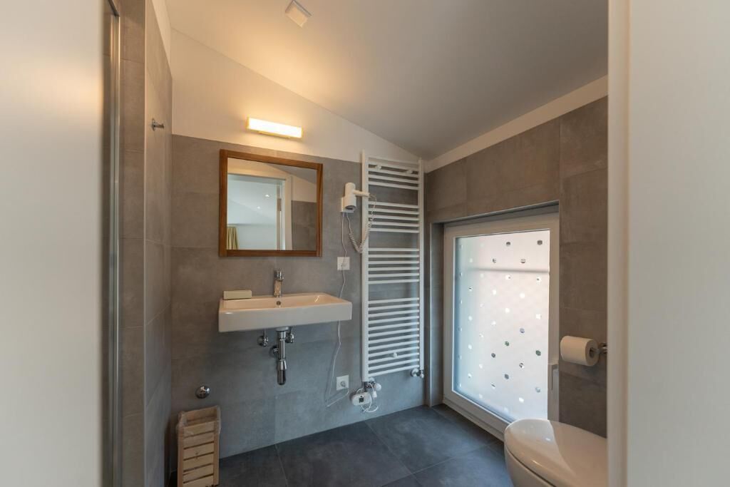 A modern bathroom with a built-in sink, a towel rack, a toilet, and a window with frosted glass.