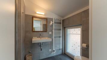 A modern bathroom with a built-in sink, a towel rack, a toilet, and a window with frosted glass.