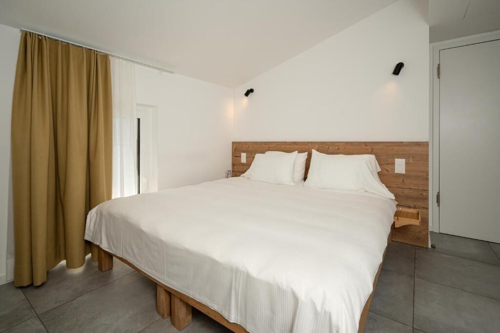 A bedroom with a large bed, wooden headboard, and a window with curtains.