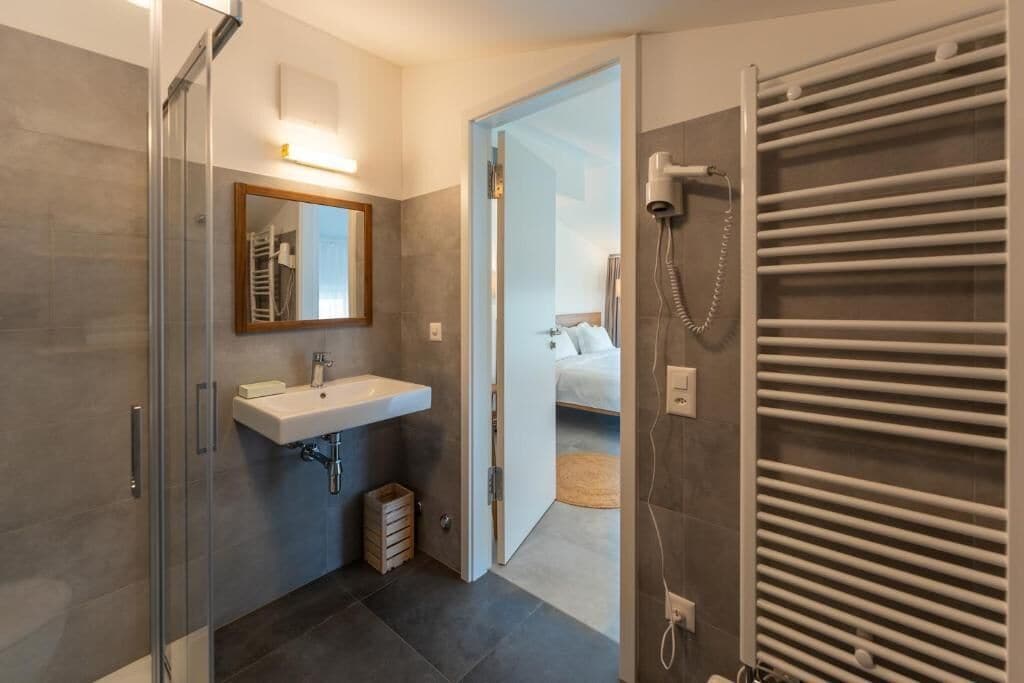 Une salle de bain moderne dotée d’une douche à parois de verre, d’un lavabo intégré et d’un porte-serviettes.