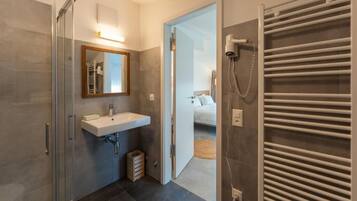 Une salle de bain moderne dotée d’une douche à parois de verre, d’un lavabo intégré et d’un porte-serviettes.
