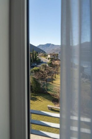 A view through a window with a mountain in the background, a road, and a fence.