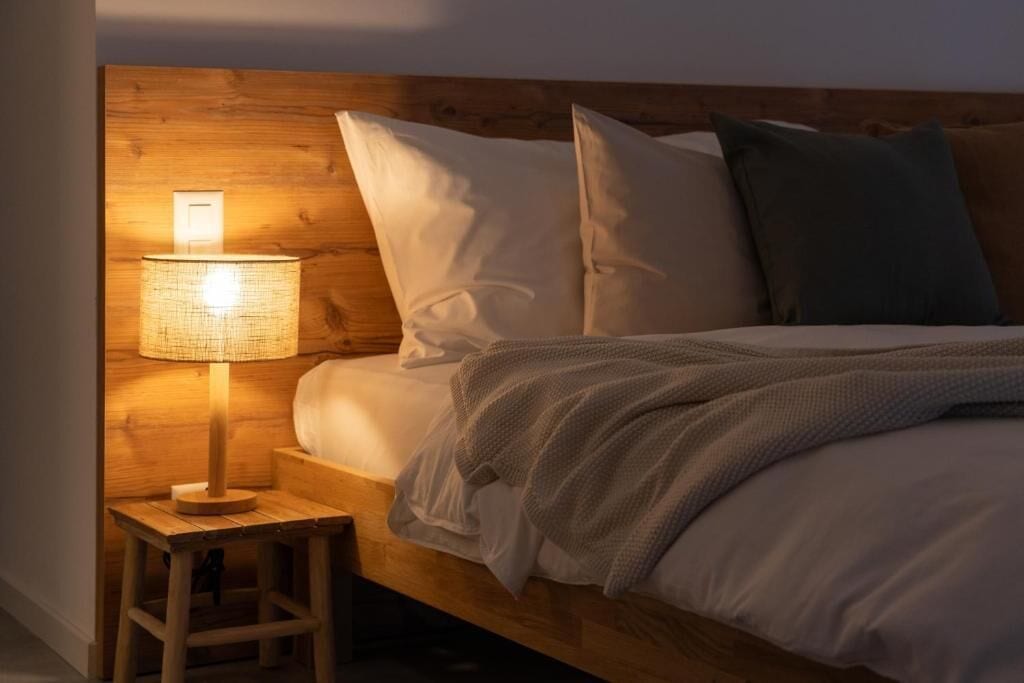 A bed with a wooden headboard, a bedside lamp, and pillows.