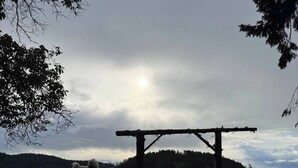 A wooden platform with a dog standing on a grassy hill overlooking a body of water. - Cozy Ocean Gateway at Spirit Bay Pet-friendly (Sooke)