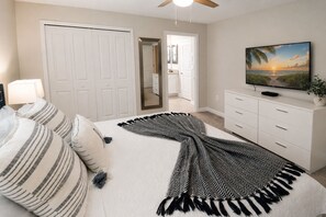 A bedroom with a bed, a television, a wardrobe, and a door leading to another room. - Luxury Disney Retreat: Private Pool + ChampionsGate Resort Access (Davenport)