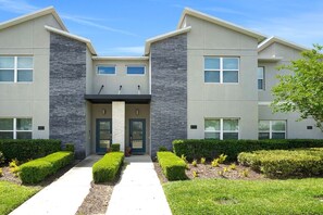 A modern two-story building with a symmetrical facade, a central entrance with double doors, and a small overhang above the doors. - Luxury Disney Retreat: Private Pool + ChampionsGate Resort Access (Davenport)