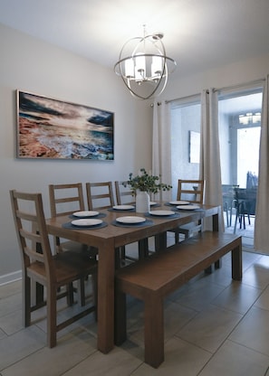 A dining area with a wooden table, chairs, a vase with flowers, and a painting on the wall. - Luxury Disney Retreat: Private Pool + ChampionsGate Resort Access (Davenport)