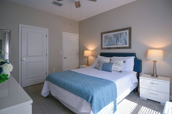 A bedroom with a bed, two bedside tables, a nightstand, a ceiling fan, and a painting on the wall. - Luxury Disney Retreat: Private Pool + ChampionsGate Resort Access (Davenport)