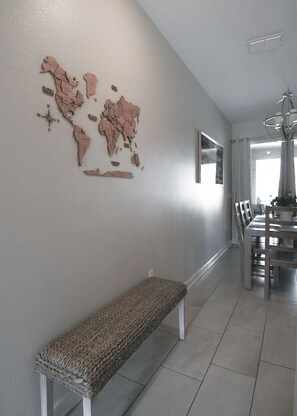A room with a bench, a dining table with chairs, and a wall-mounted world map. - Luxury Disney Retreat: Private Pool + ChampionsGate Resort Access (Davenport)