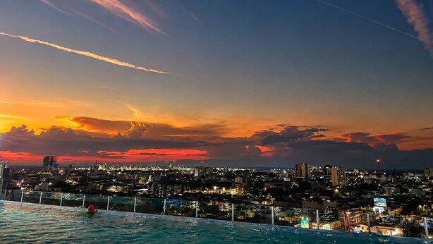 A cityscape at sunset with a pool in the foreground.