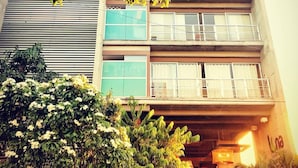 A multi-story building with balconies, large windows, and a well-maintained garden area.