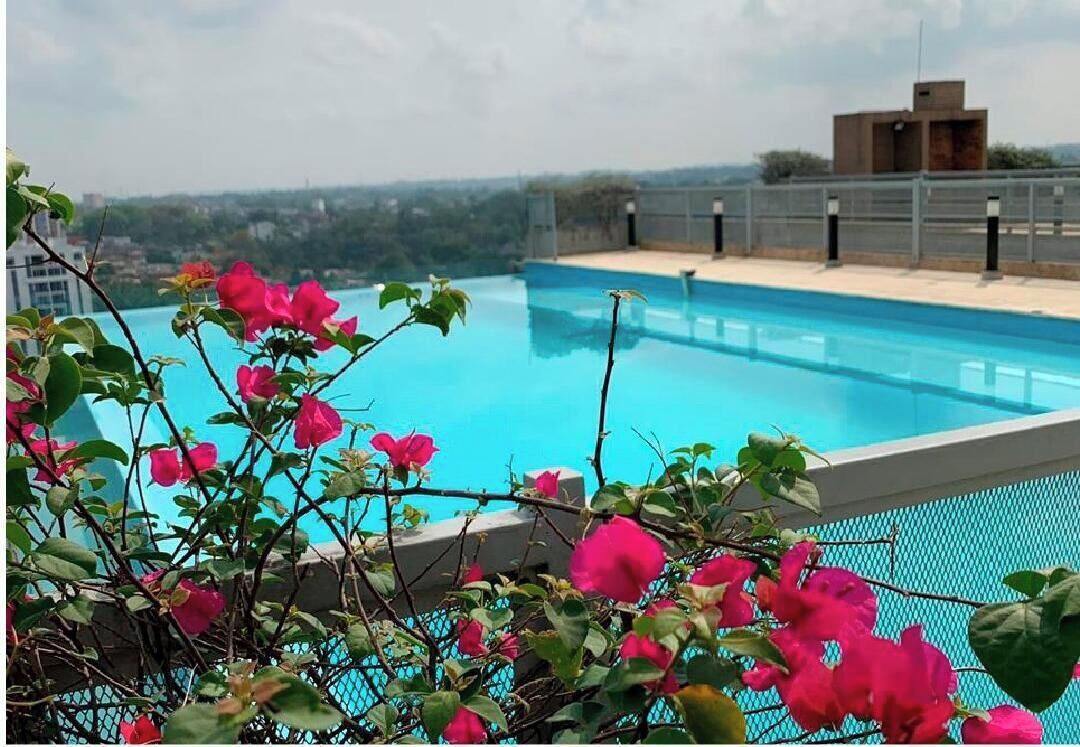 Una piscina en la azotea con vistas a un paisaje urbano.