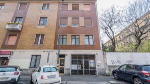 Un edificio de varios pisos con entrada a nivel de calle, una puerta visible y una reja.