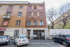 A multi-story building with a ground-floor entrance, a visible door, and a barred gate. - Bright Milan Apartment | Downtown & Terrace (Milano)