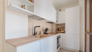 Una cocina moderna con armarios blancos, una encimera de madera, un grifo negro, una tetera y una cafetera.