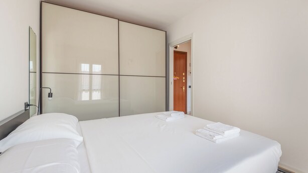 Una habitación de hotel con cama, armario y puerta.