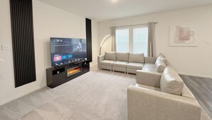 A modern living room with a flat-screen TV, a sofa, a coffee table, and a fireplace. - Modern 3br/2.5ba • 3 king bed • Gameroom • Pets OK (Montgomery)