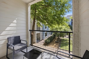 A balcony with a view of a tree and a building. - Solis Stay 1-King Bed+Sofa Bed in Frisco with pool and gym access (Frisco)