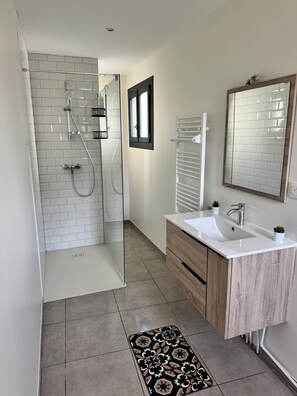 Un bagno moderno con doccia, lavabo e specchio.