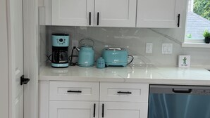 Eine Küche mit weißen Schränken, einer Kaffeemaschine, einem Wasserkocher und einem Toaster auf der Arbeitsfläche.